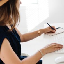 A woman sitting at a desk writing on a notepad.